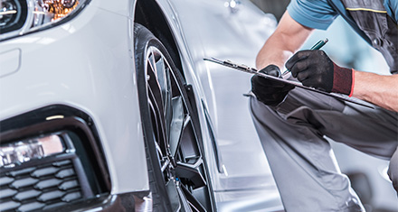 a person writing on a clipboard inspecting a car