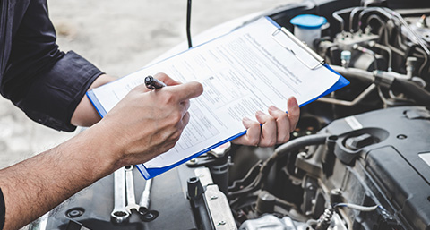 a man holding a clipboard over the engine of a car