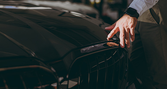 a man placing his hand on the bonnet of a black car